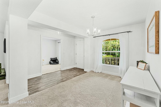 interior space with carpet floors, a textured ceiling, and an inviting chandelier