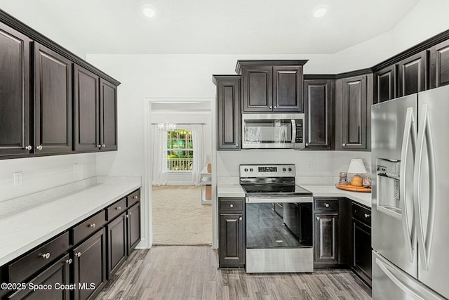 kitchen with appliances with stainless steel finishes, dark brown cabinetry, and light hardwood / wood-style flooring