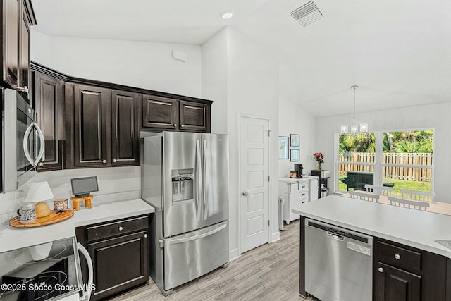 kitchen featuring appliances with stainless steel finishes, pendant lighting, lofted ceiling, dark brown cabinets, and light wood-type flooring