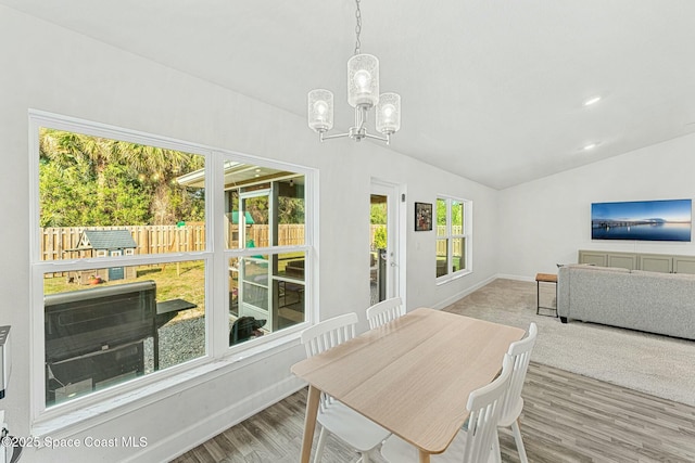 dining area with hardwood / wood-style floors, a notable chandelier, and vaulted ceiling