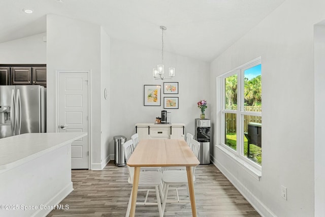 dining space featuring vaulted ceiling, plenty of natural light, hardwood / wood-style floors, and a chandelier