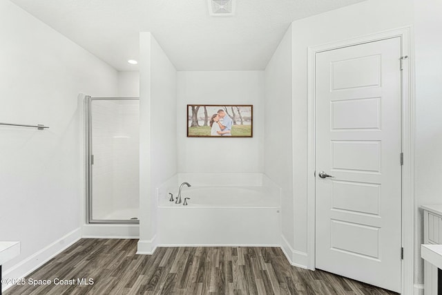 bathroom featuring plus walk in shower and hardwood / wood-style floors