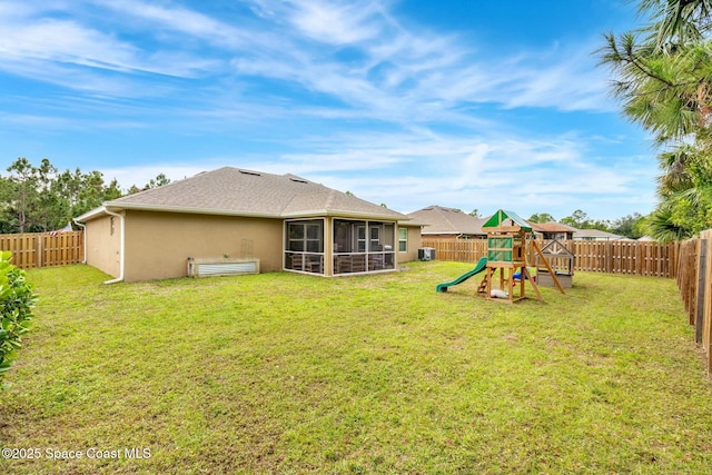 rear view of house featuring a yard, a sunroom, and a playground