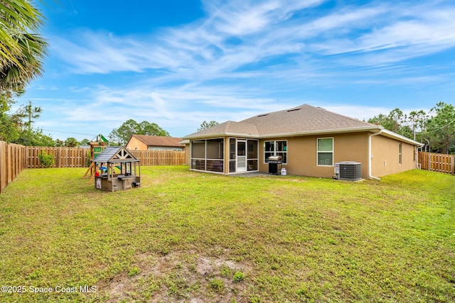 back of house featuring a playground, central air condition unit, a sunroom, and a lawn