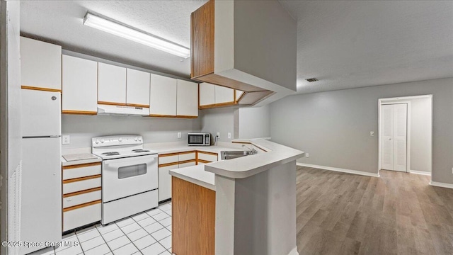 kitchen with kitchen peninsula, sink, white appliances, white cabinetry, and a textured ceiling