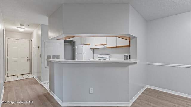 kitchen featuring range, white cabinets, white refrigerator, and kitchen peninsula