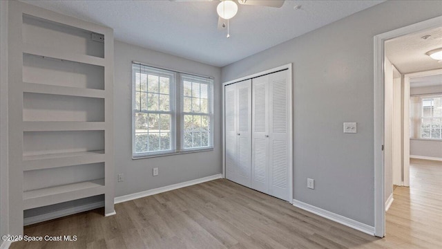 unfurnished bedroom featuring ceiling fan, light hardwood / wood-style floors, a textured ceiling, and a closet