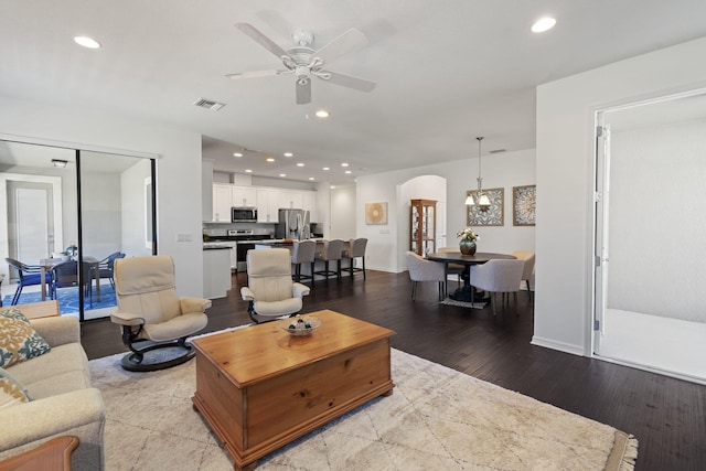 living room with ceiling fan with notable chandelier and light hardwood / wood-style flooring