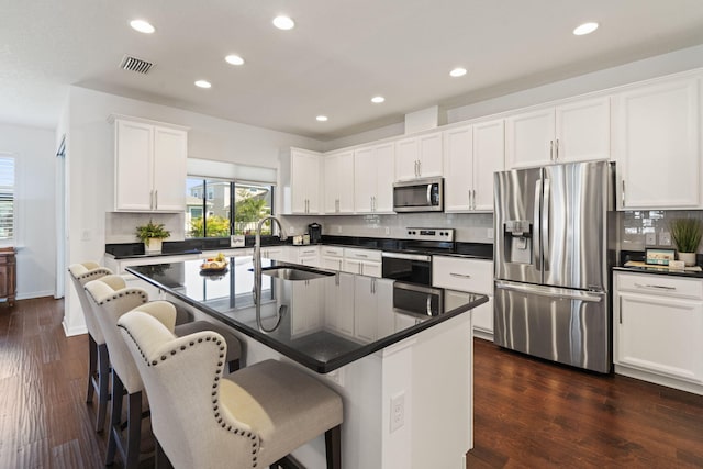 kitchen featuring stainless steel appliances, white cabinets, sink, and a breakfast bar