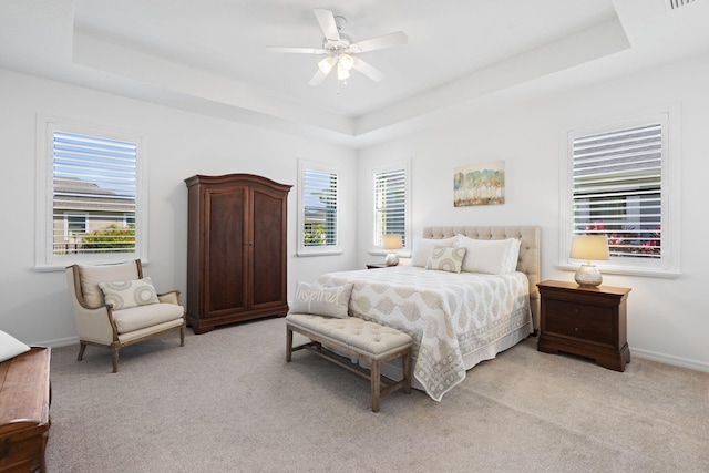 bedroom featuring light carpet, ceiling fan, and a tray ceiling