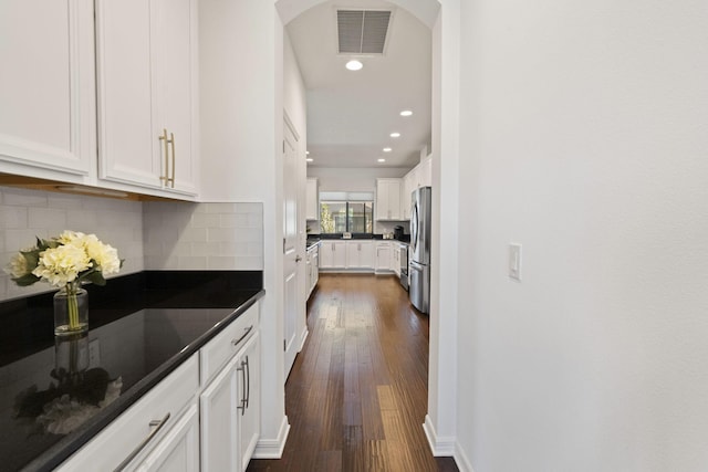 kitchen featuring white cabinetry, backsplash, dark hardwood / wood-style floors, and stainless steel refrigerator