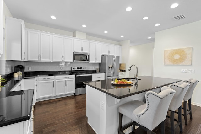 kitchen featuring a breakfast bar area, stainless steel appliances, a center island, sink, and white cabinetry