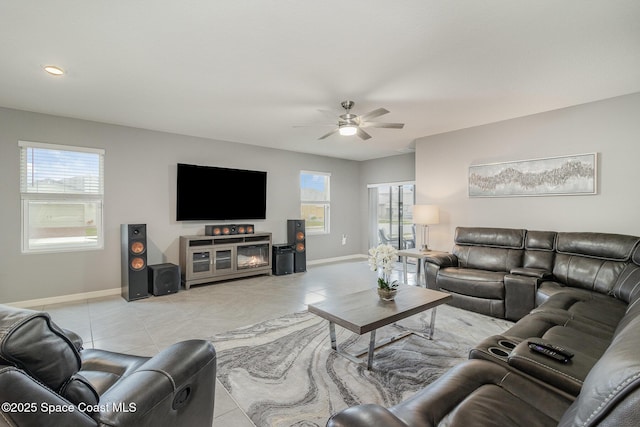 living room featuring ceiling fan, a fireplace, and light tile patterned floors