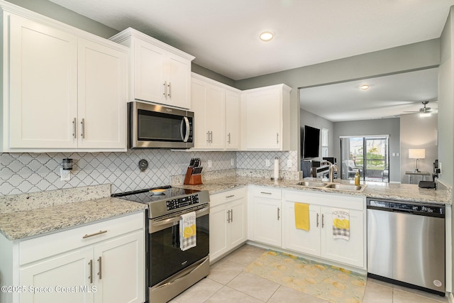 kitchen featuring light tile patterned flooring, appliances with stainless steel finishes, white cabinetry, sink, and decorative backsplash