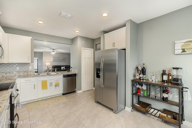 kitchen featuring light tile patterned flooring, sink, light stone counters, stainless steel appliances, and white cabinets