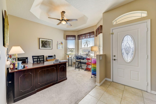 carpeted entryway with a textured ceiling, ceiling fan, and a tray ceiling