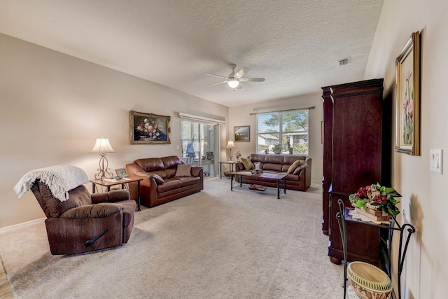 carpeted living room with a textured ceiling and ceiling fan