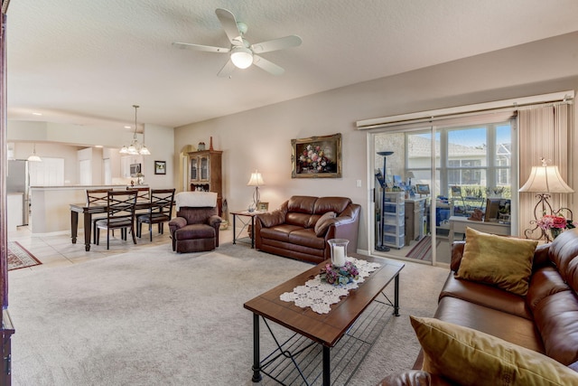 living room with a textured ceiling, light colored carpet, and ceiling fan with notable chandelier