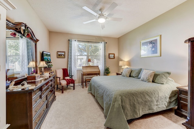 bedroom featuring a textured ceiling, ceiling fan, and light colored carpet