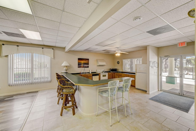 kitchen featuring sink, a drop ceiling, white appliances, ceiling fan, and kitchen peninsula