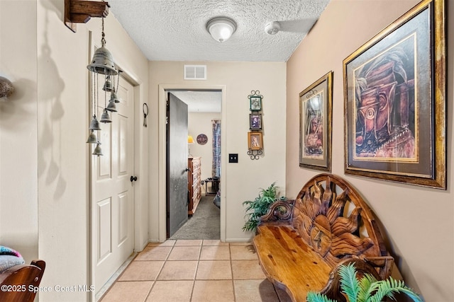 corridor featuring light tile patterned floors and a textured ceiling