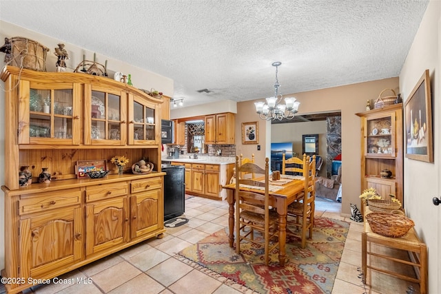 dining space with a notable chandelier, light tile patterned floors, sink, and a textured ceiling