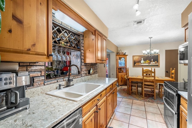 kitchen featuring pendant lighting, tasteful backsplash, sink, a chandelier, and stainless steel appliances