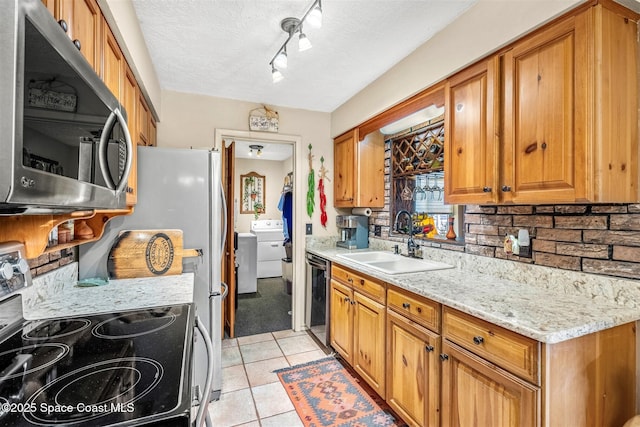 kitchen with sink, light tile patterned floors, electric range, light stone counters, and washer / clothes dryer