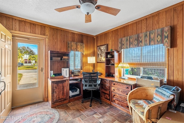 home office featuring ceiling fan, wooden walls, and a textured ceiling