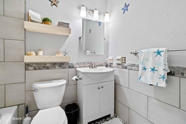 bathroom with toilet, tile walls, and vanity