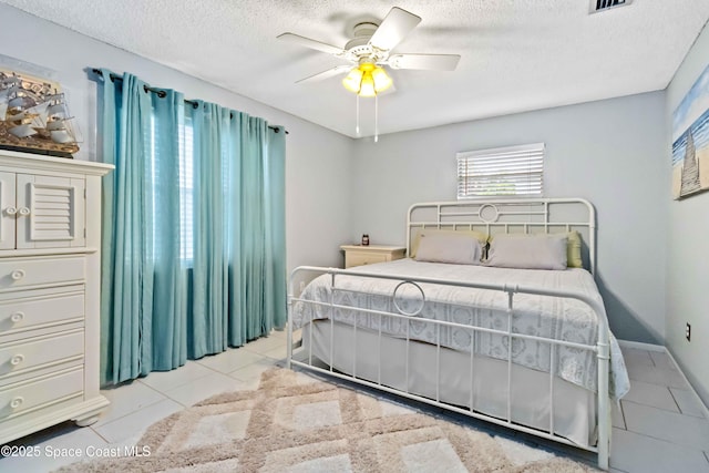 tiled bedroom with a textured ceiling and ceiling fan