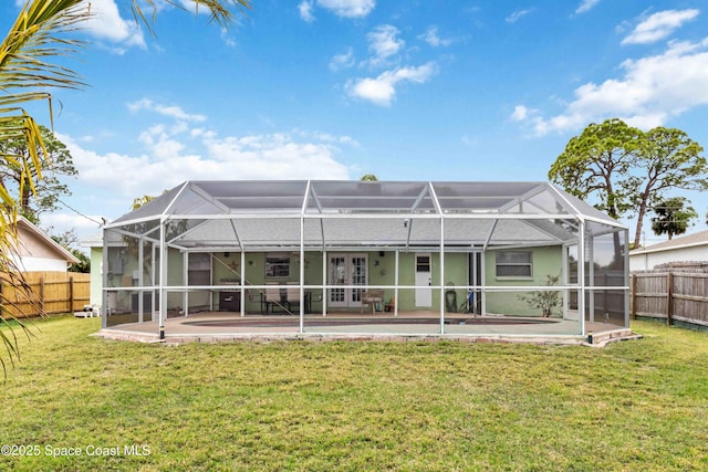 rear view of property featuring glass enclosure, a patio area, french doors, and a yard