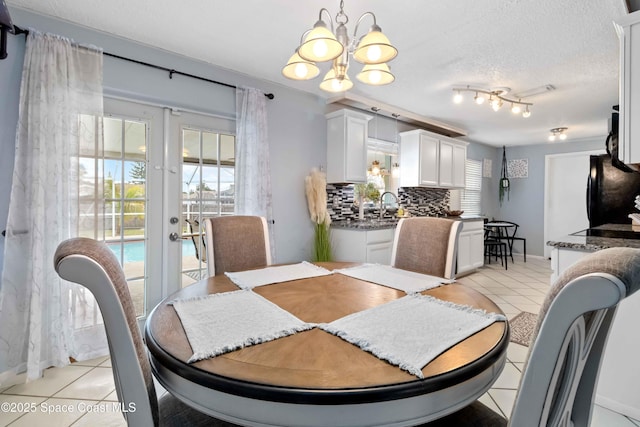 dining space featuring a textured ceiling, light tile patterned floors, french doors, and an inviting chandelier