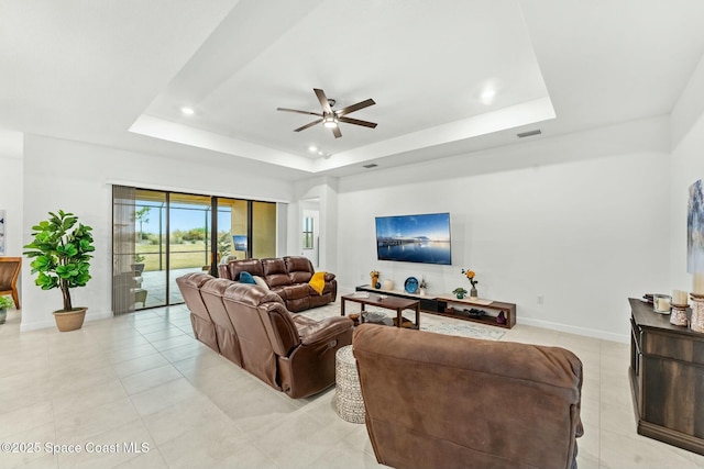 living room with ceiling fan, light tile patterned flooring, and a tray ceiling