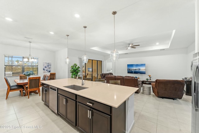 kitchen featuring an island with sink, ceiling fan with notable chandelier, a raised ceiling, and sink