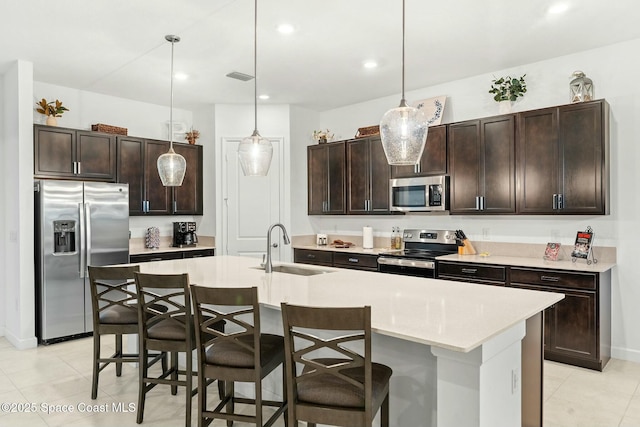 kitchen with stainless steel appliances, pendant lighting, dark brown cabinetry, and sink