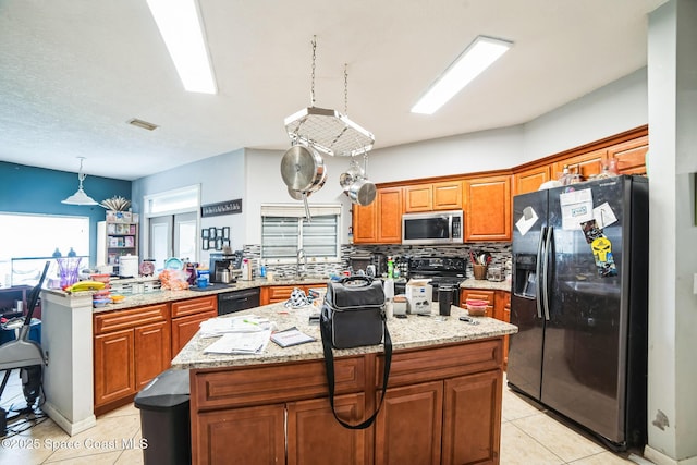 kitchen with light tile patterned floors, black appliances, decorative backsplash, a kitchen island, and sink