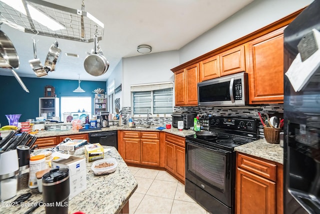 kitchen featuring hanging light fixtures, light tile patterned floors, black appliances, decorative backsplash, and sink