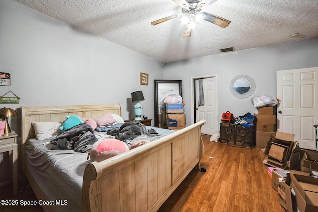 bedroom with a textured ceiling, ceiling fan, and dark hardwood / wood-style floors