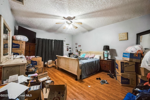 bedroom featuring hardwood / wood-style flooring, a textured ceiling, and ceiling fan