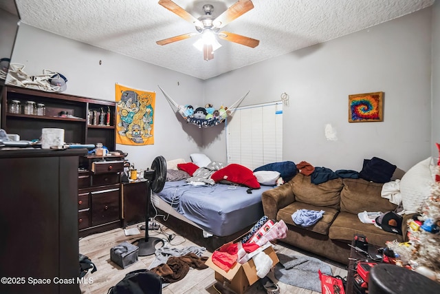 bedroom with a textured ceiling, ceiling fan, and light hardwood / wood-style flooring