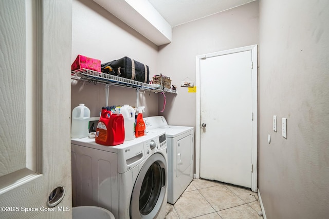 laundry area with washer and dryer and light tile patterned floors