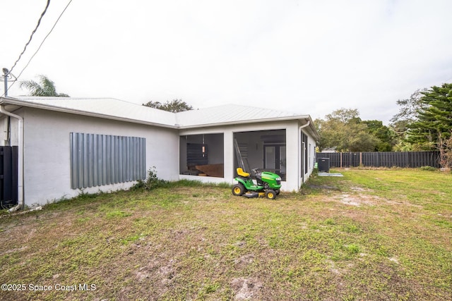 back of property with central air condition unit, a lawn, and a sunroom