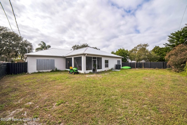 back of property with a sunroom and a lawn