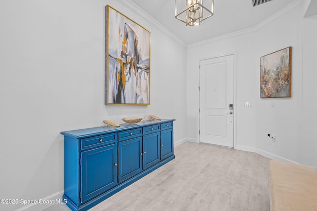 foyer entrance featuring light hardwood / wood-style floors, ornamental molding, and a notable chandelier