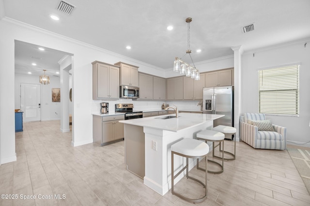 kitchen featuring decorative light fixtures, sink, an island with sink, a breakfast bar area, and stainless steel appliances