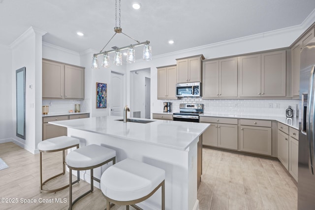 kitchen featuring decorative light fixtures, stainless steel appliances, tasteful backsplash, sink, and a center island with sink