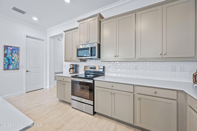 kitchen with tasteful backsplash, gray cabinetry, appliances with stainless steel finishes, and crown molding