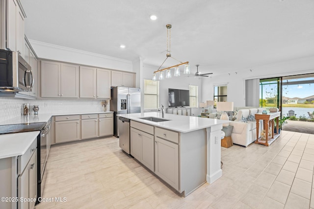 kitchen featuring a center island with sink, sink, hanging light fixtures, appliances with stainless steel finishes, and ceiling fan with notable chandelier