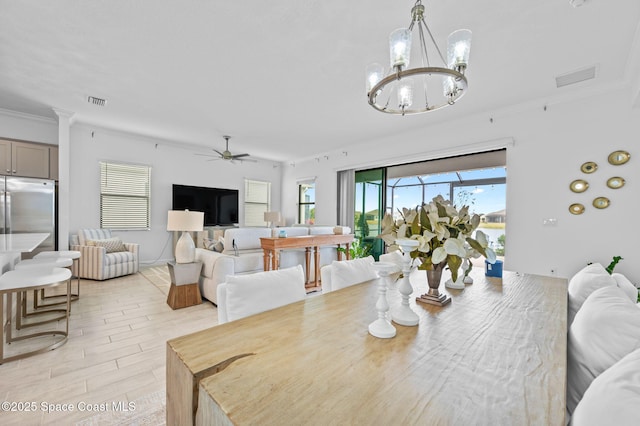 dining room featuring light wood-type flooring, crown molding, and ceiling fan with notable chandelier